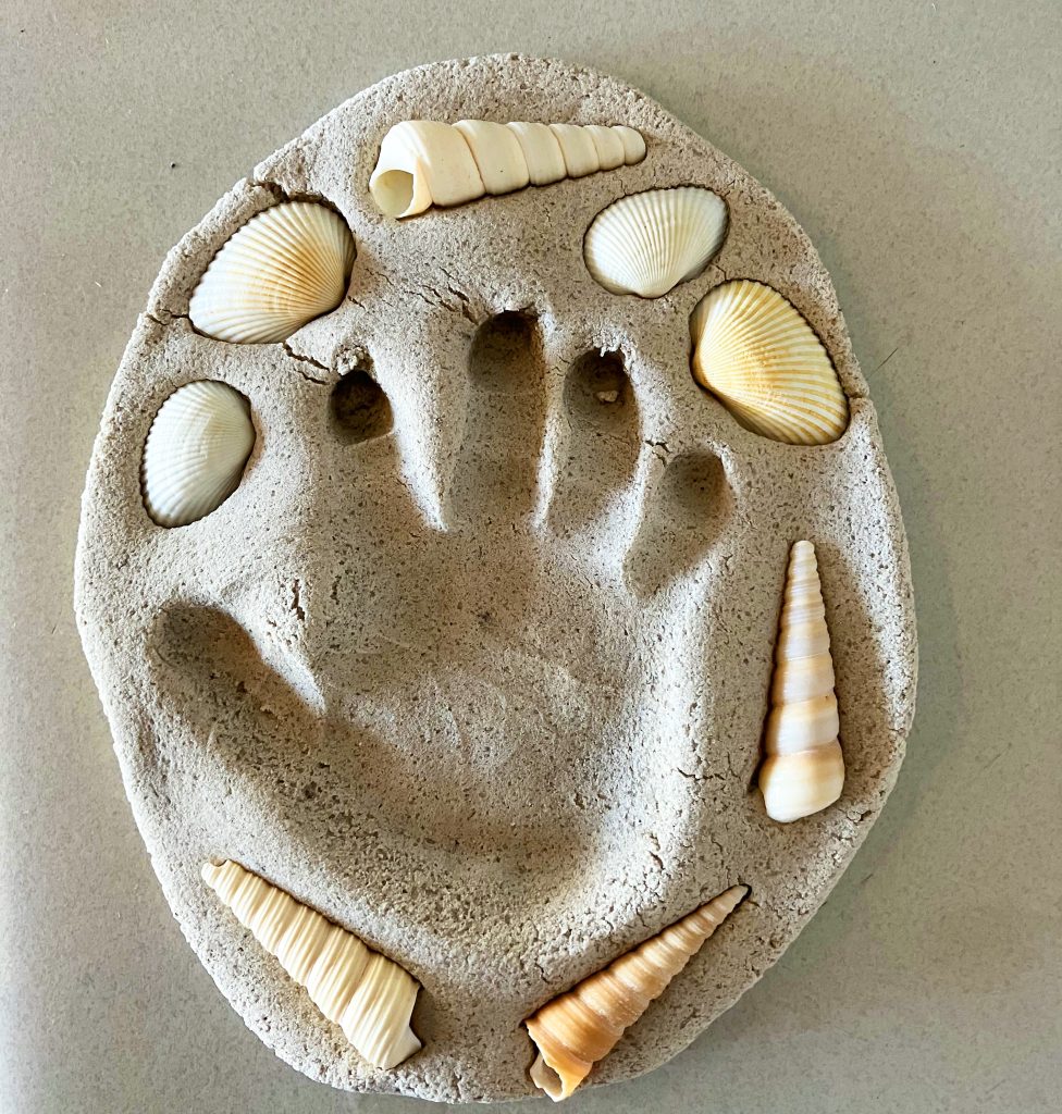 A photo of a cast of a handprint surrounded by shells